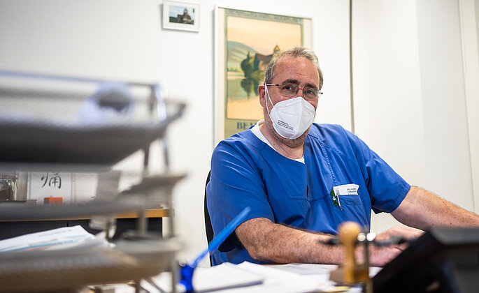 Bild von Dr. Ralph Ruwoldt, Chefarzt der Anästhesie, Intensiv- und Notfallmedizin in den Dill-Kliniken in Dillenburg in seinem Büro am Schreibtisch. 